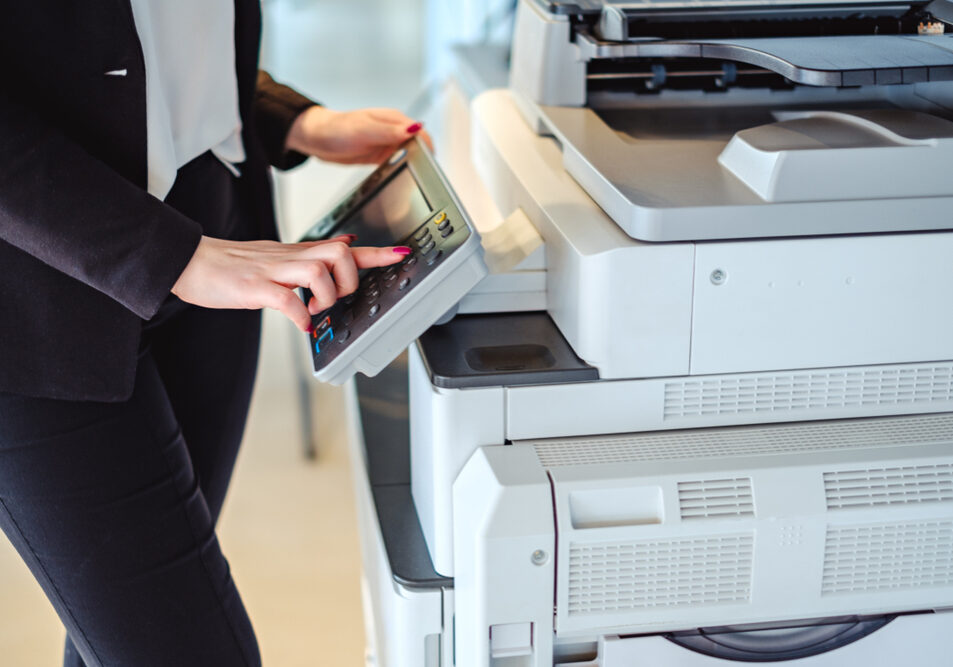 Woman,Standing,And,Pressing,Button,On,A,Copy,Machine,In