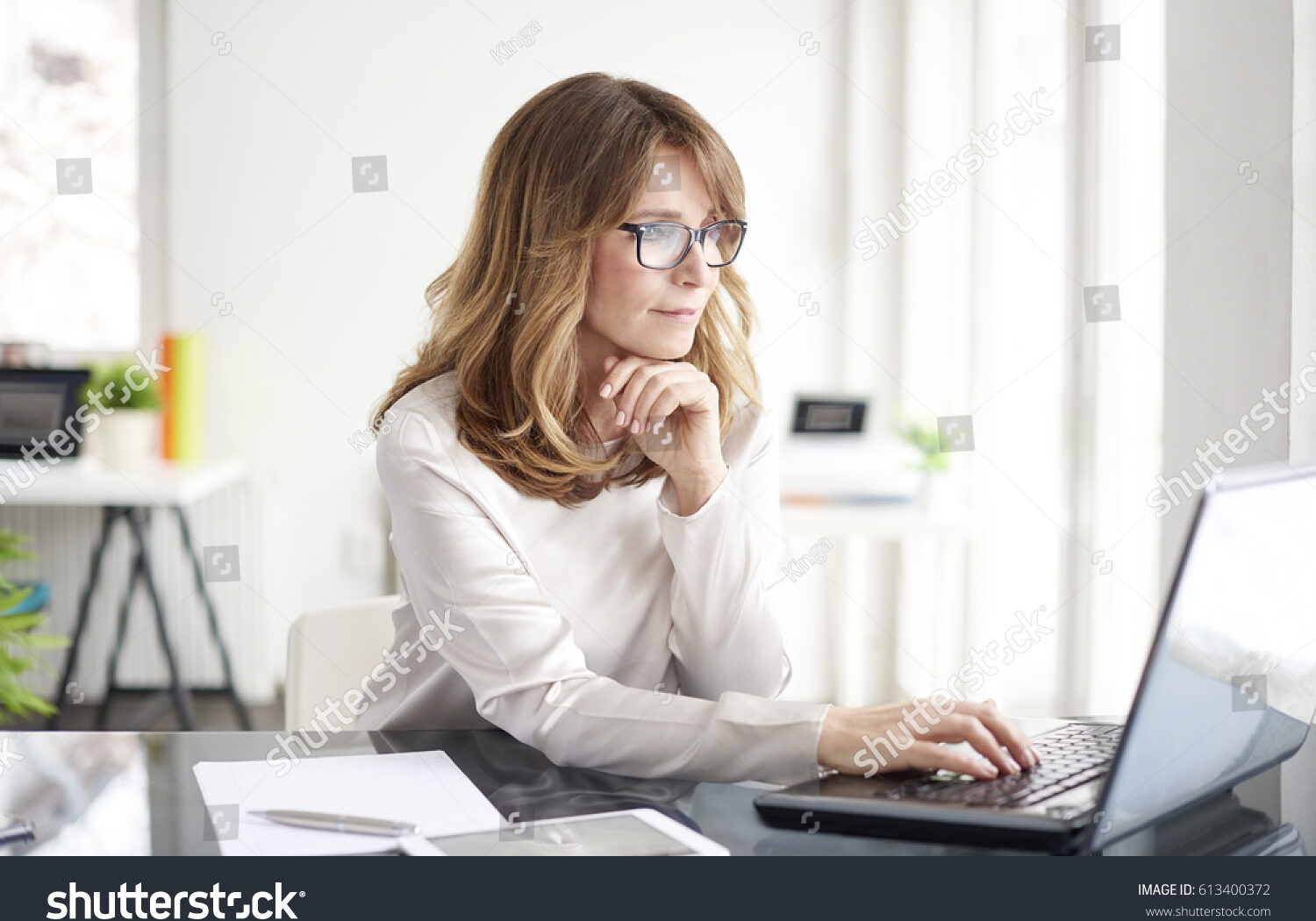 stock-photo-shot-of-an-attractive-mature-businesswoman-working-on-laptop-in-her-workstation-613400372
